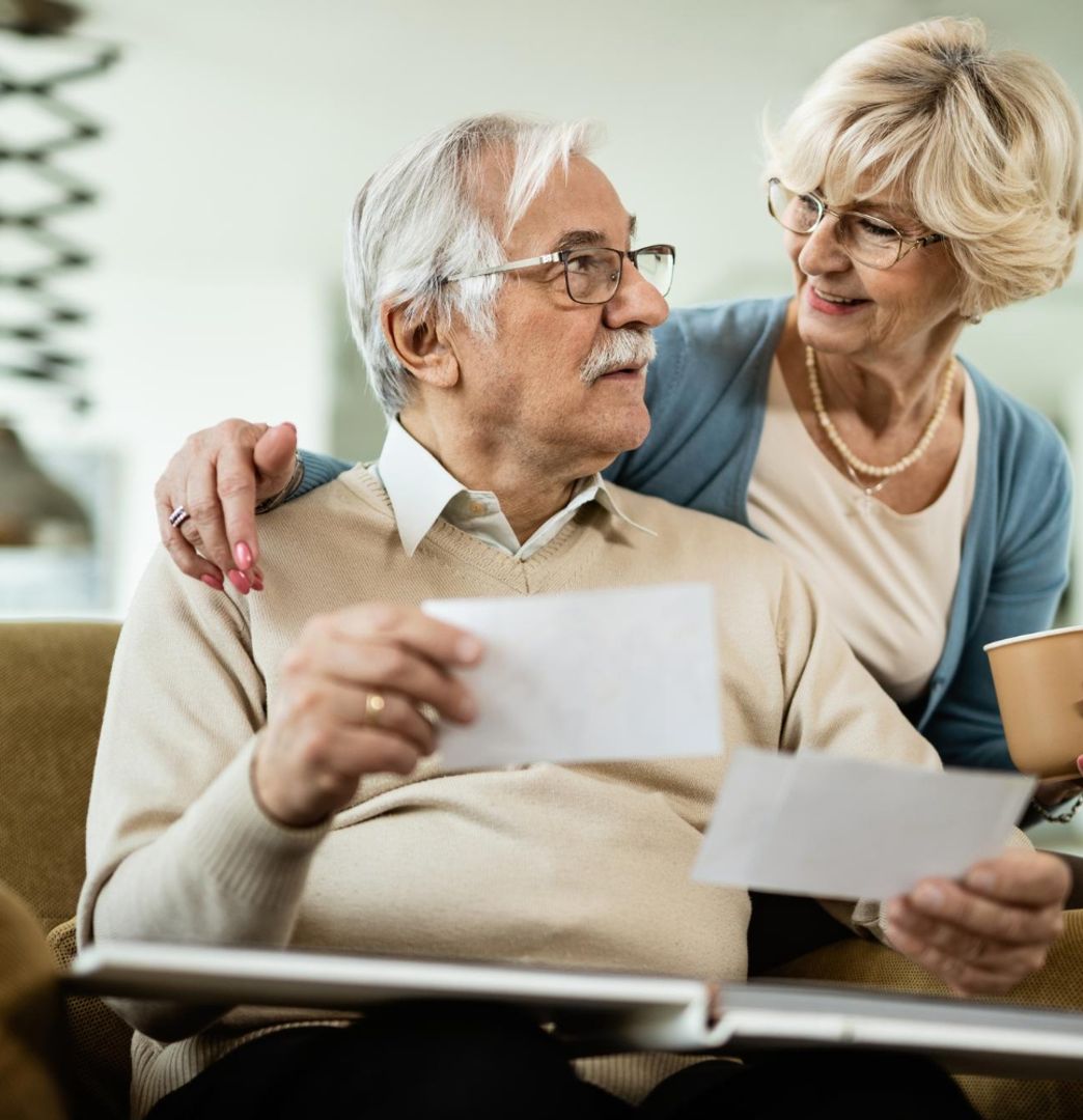 Old retired couple sitting on couch with
        papers 